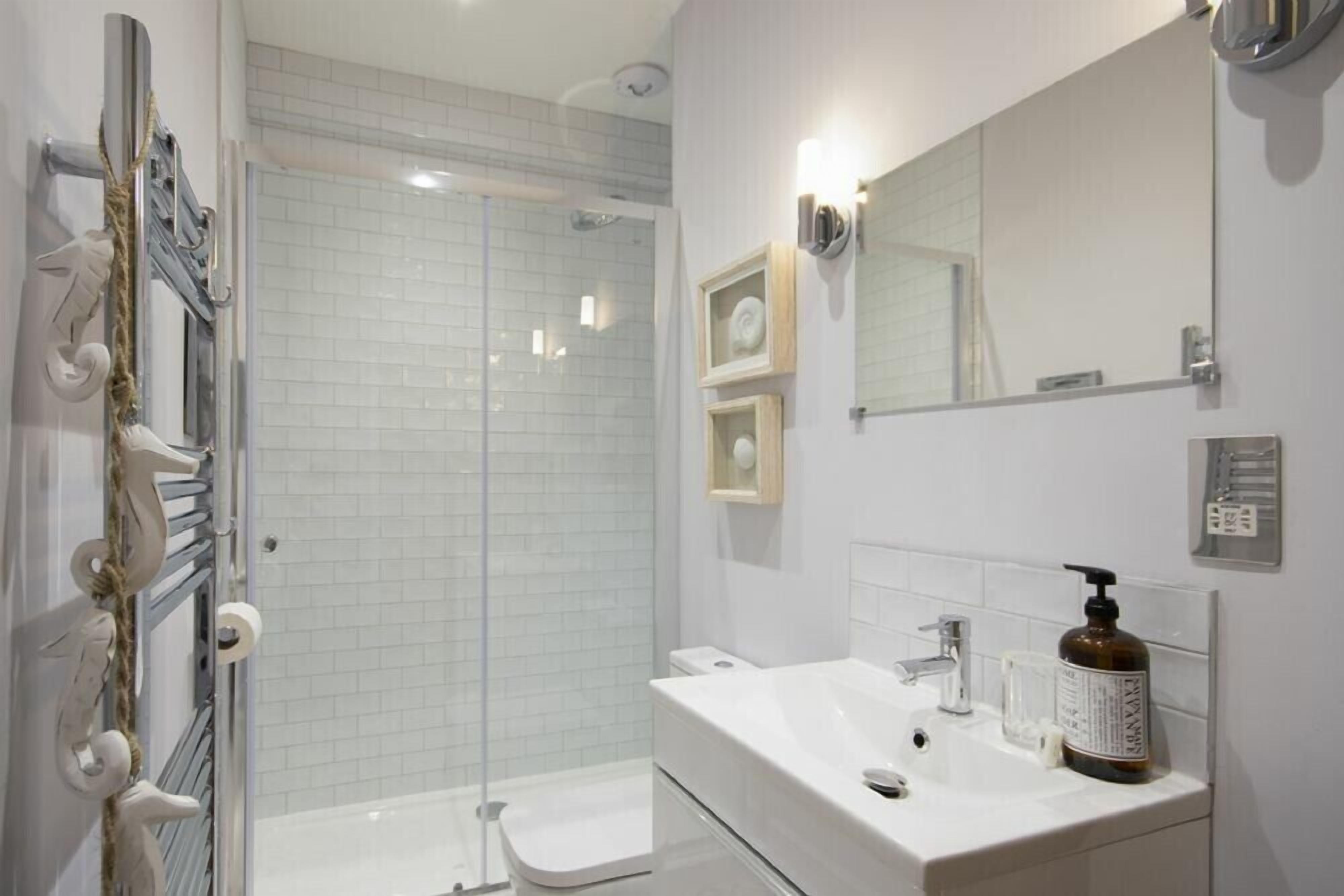 A modern bathroom with a glass shower enclosure, a white sink, and a large mirror.