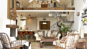 A spacious living area with a high ceiling, a staircase, and a dining area. - Marmalade Cottage (Seahouses)