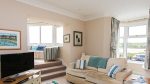 A living room with a sofa, TV, and a view of the outdoors. - The Beach House, Alnmouth (Alnwick)