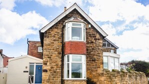 A stone house with a gabled roof, a small porch, and a blue door. - The Beach House, Alnmouth (Alnwick)