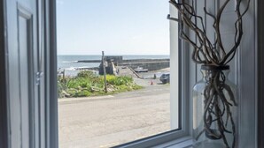 A coastal view from a window with a vase of branches. - Creel Cottage, Craster (Alnwick)