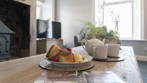 A breakfast setting with a plate of food, a teapot, and cups on a wooden table. - Creel Cottage, Craster (Alnwick)