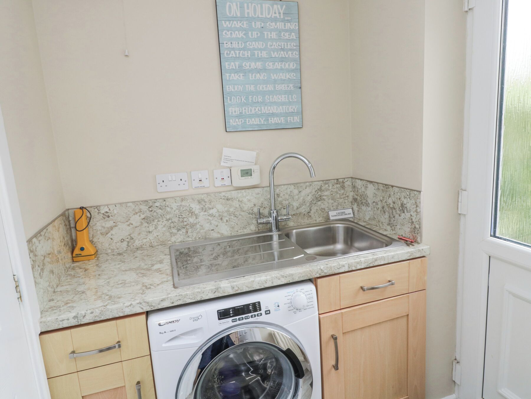 A compact kitchen with a washing machine, a sink, and a marble countertop.