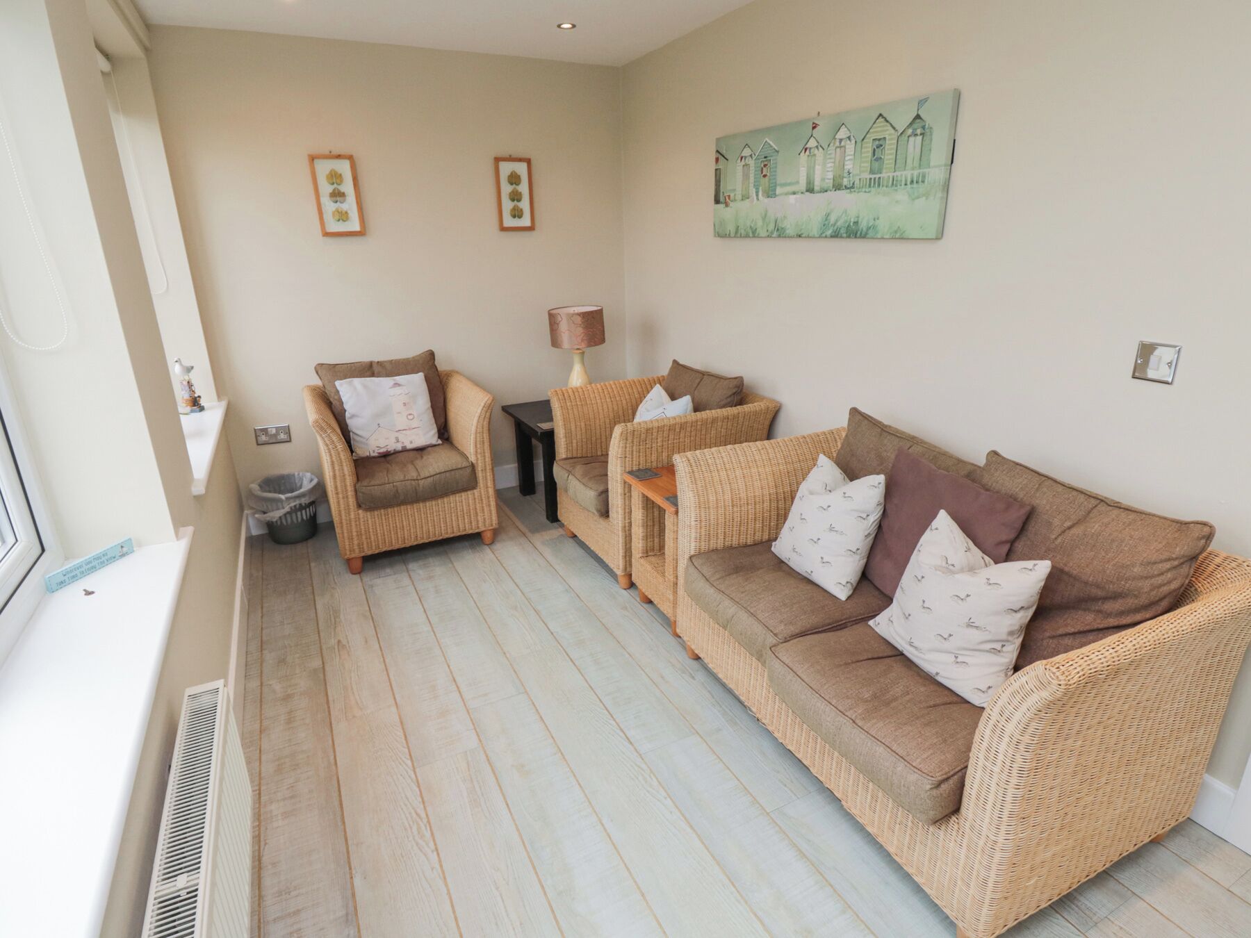 A living room with wicker furniture, a painting on the wall, and a radiator.