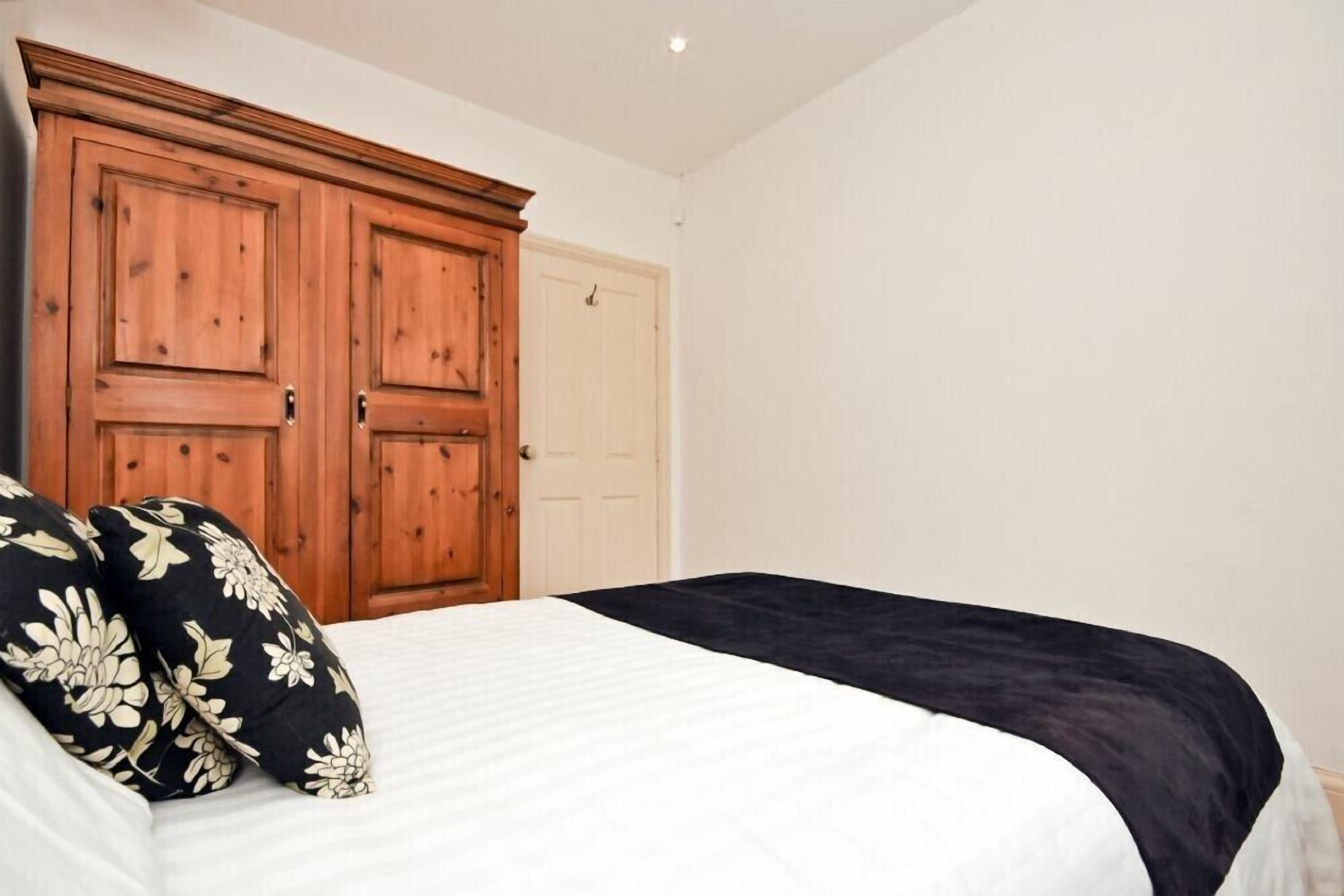 Een slaapkamer met een bed, twee houten deuren en een witte muur.