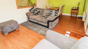 A furnished living room with a sofa, ottoman, and a dining area with a table and chairs.