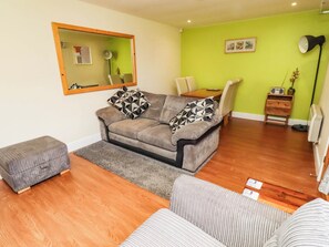 A furnished living room with a sofa, ottoman, and a dining area with a table and chairs.