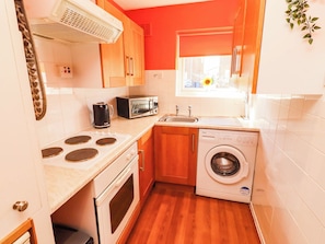 A compact kitchen with a stove, microwave, sink, and washing machine.