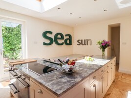 A modern kitchen with a large island, a built-in stove, and a backsplash.