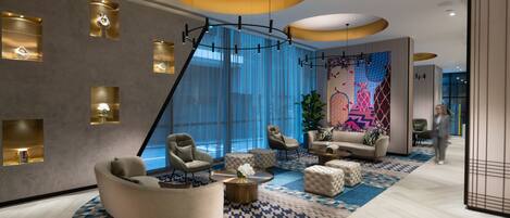 Um hall de hotel moderno com área de estar em curva, uma janela grande e uma parede colorida com arte abstrata.