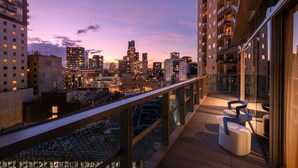 Un balcón con vista a la ciudad, muebles modernos y barandilla de cristal.