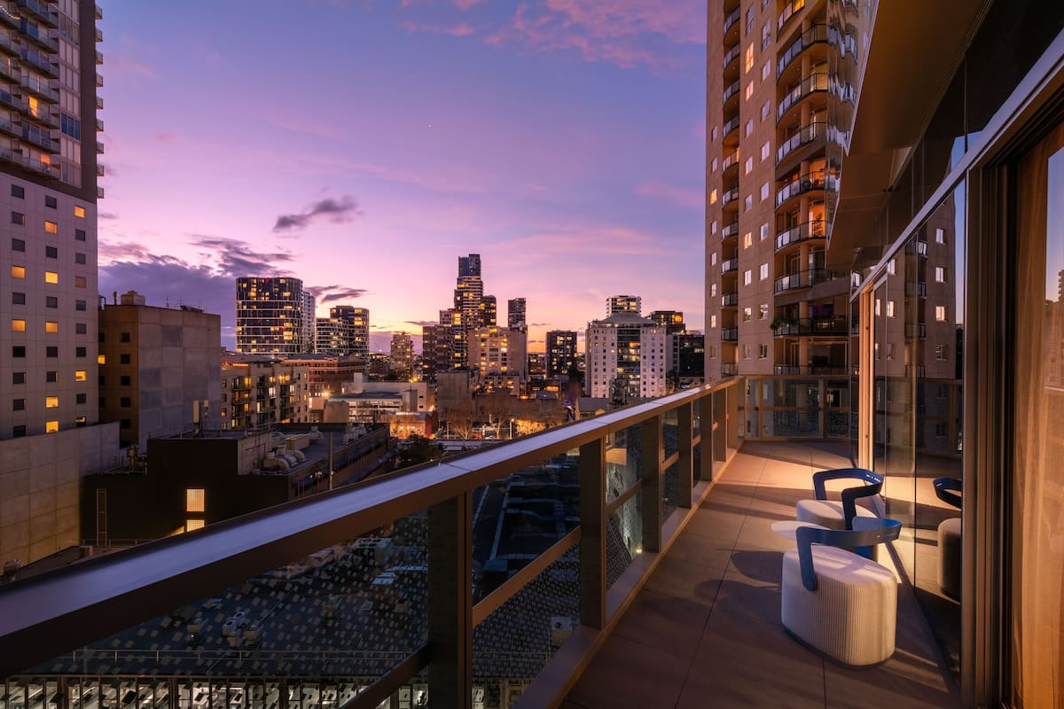 A balcony with a city view, modern furniture, and a glass railing.
