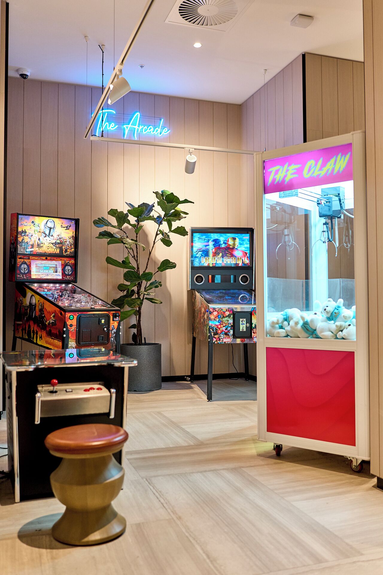 Un área de juegos con máquinas de arcade, un letrero de neón y una máquina de garra.