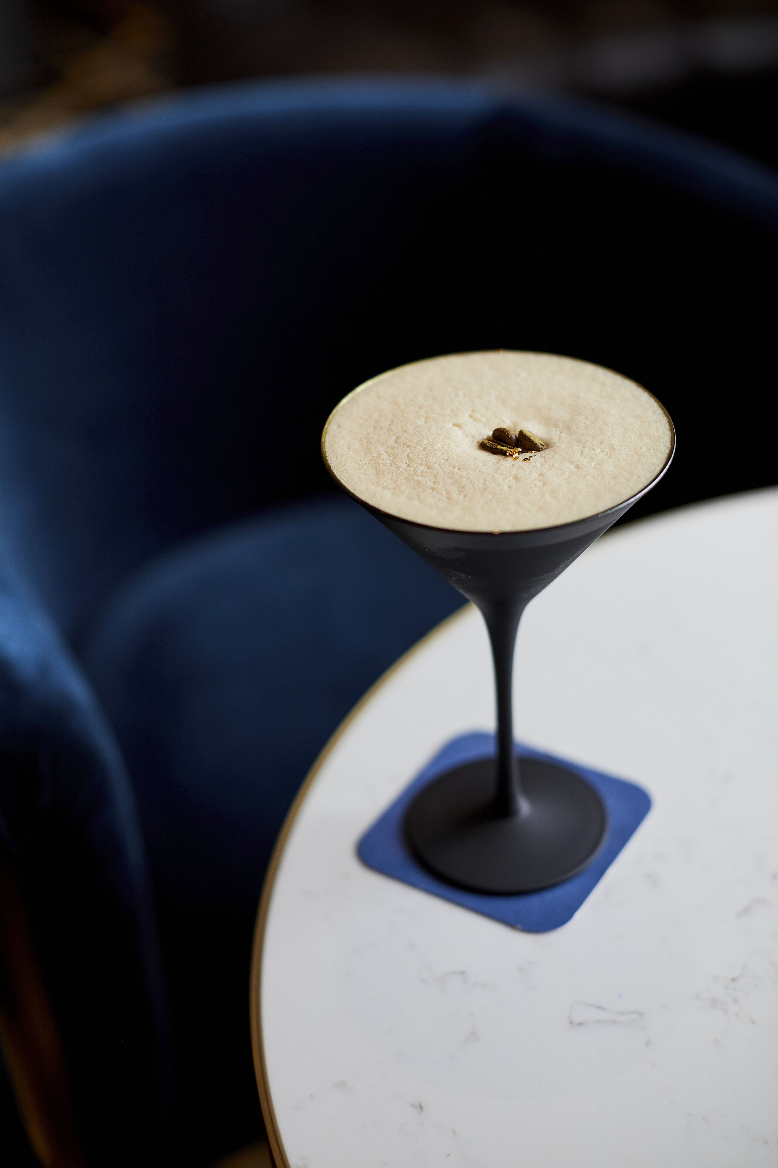 A martini glass with a frothy top on a white table.