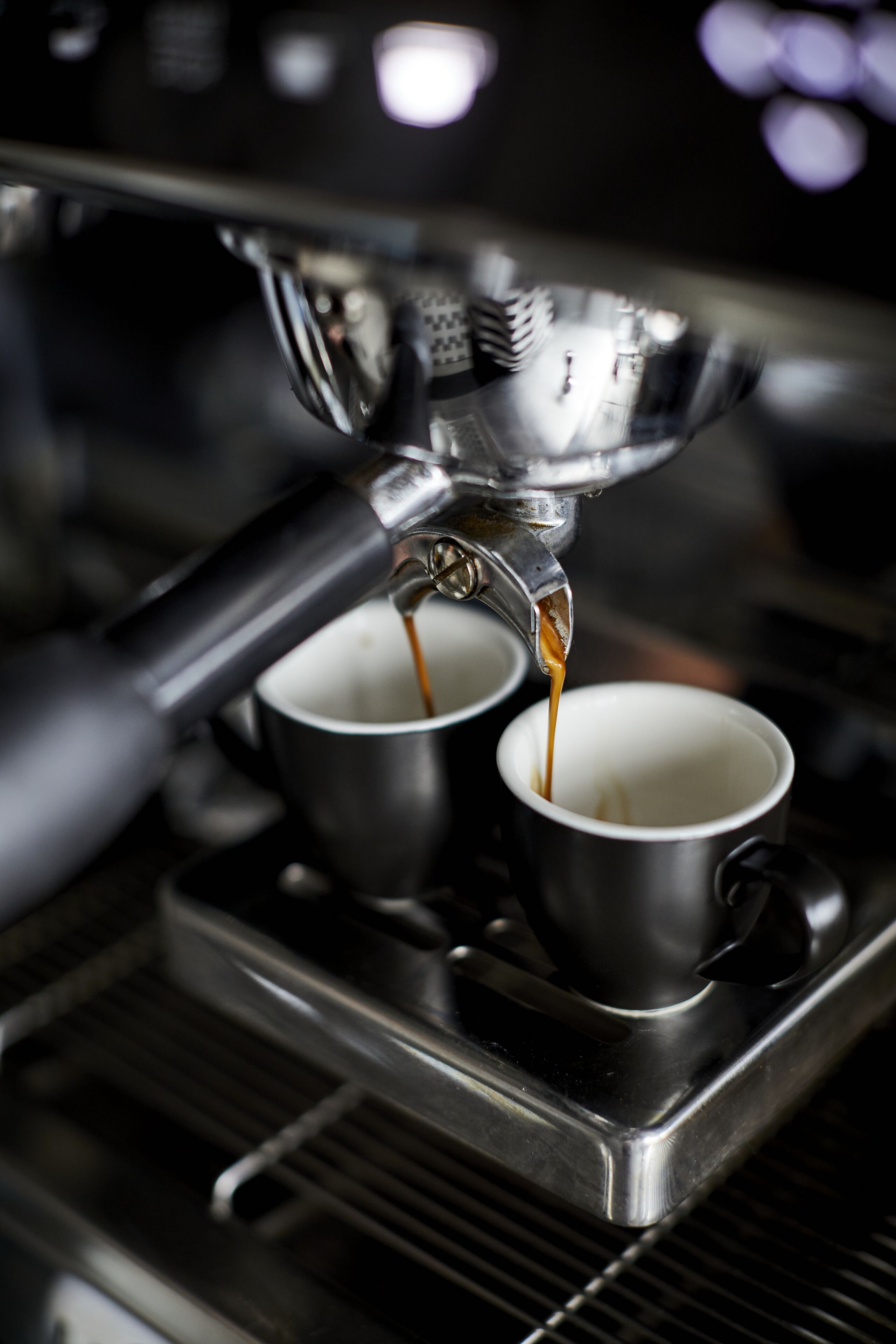 A coffee machine dispensing espresso into two cups.