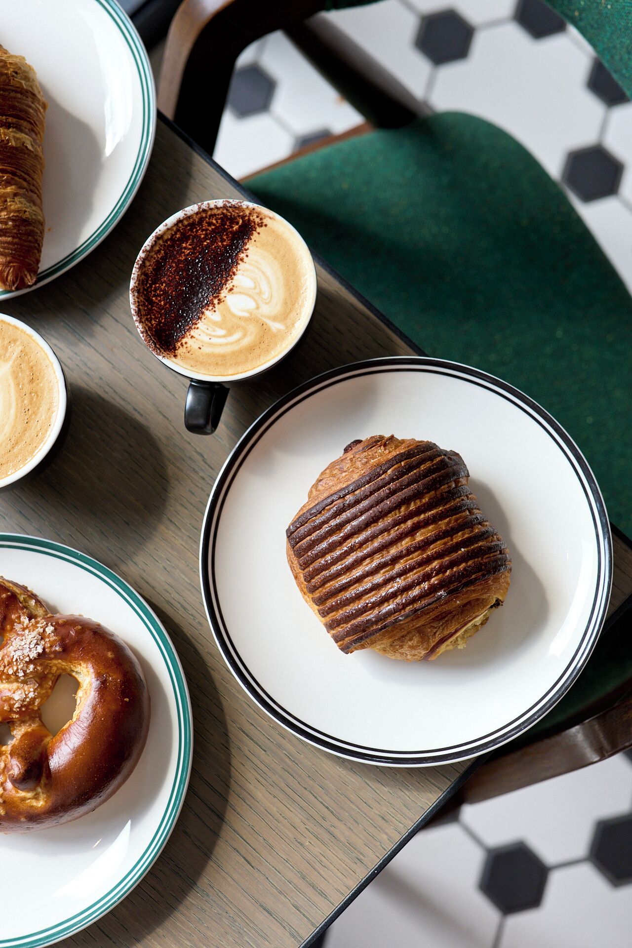 A table with a pastry, a cup of coffee, and a pretzel.