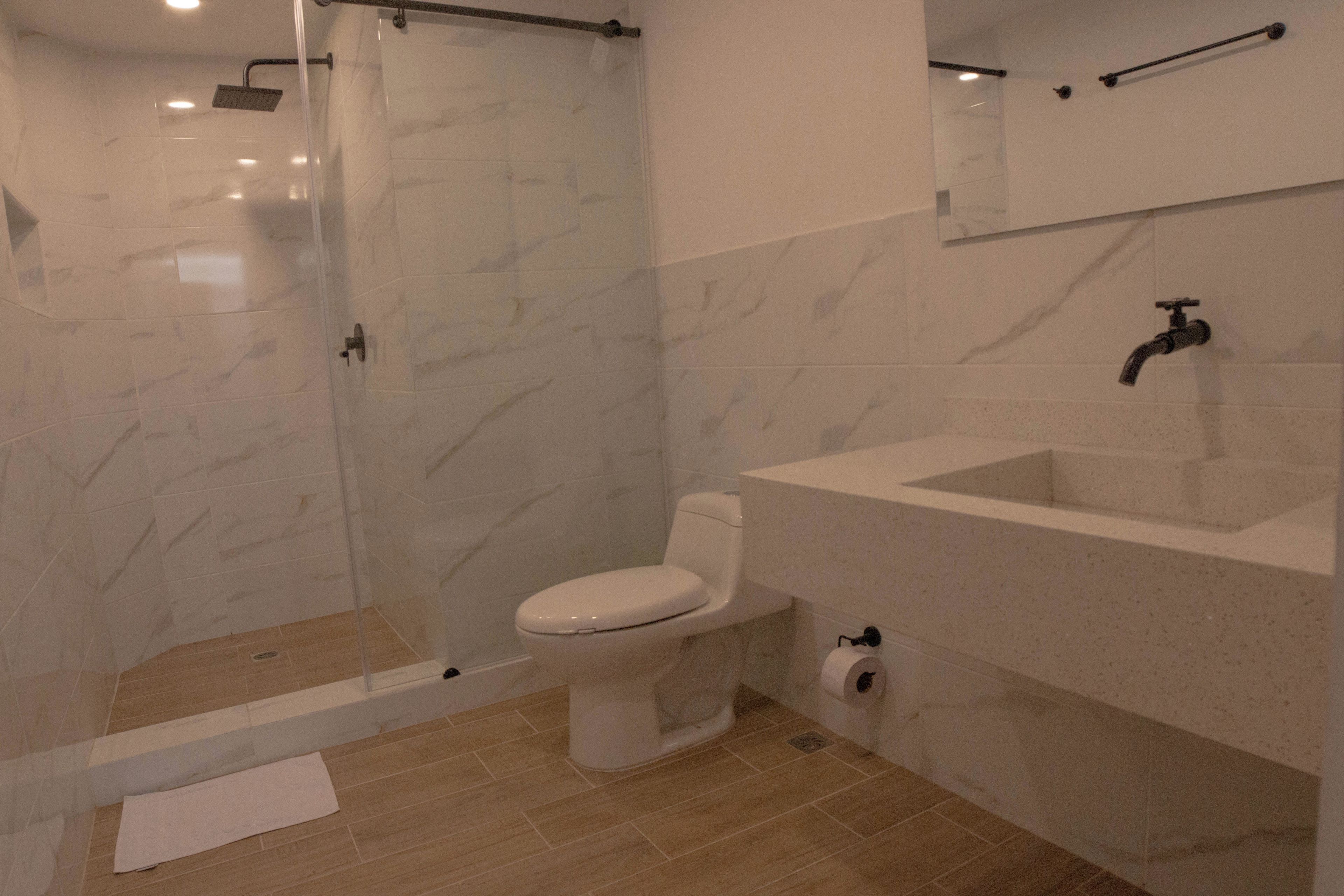 Une salle de bain avec une douche à parois de verre, des toilettes et un lavabo.