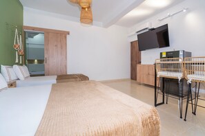Une chambre moderne avec un grand lit, un bureau avec une chaise, une télévision et un coin cuisine.