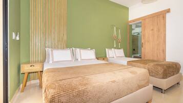 A bedroom with two beds, a wooden wardrobe, a bedside table, and a mirror.