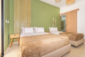 A bedroom with two beds, a wooden wardrobe, a bedside table, and a mirror. - Hotel La Casona Laureles Medellin (Medellín)