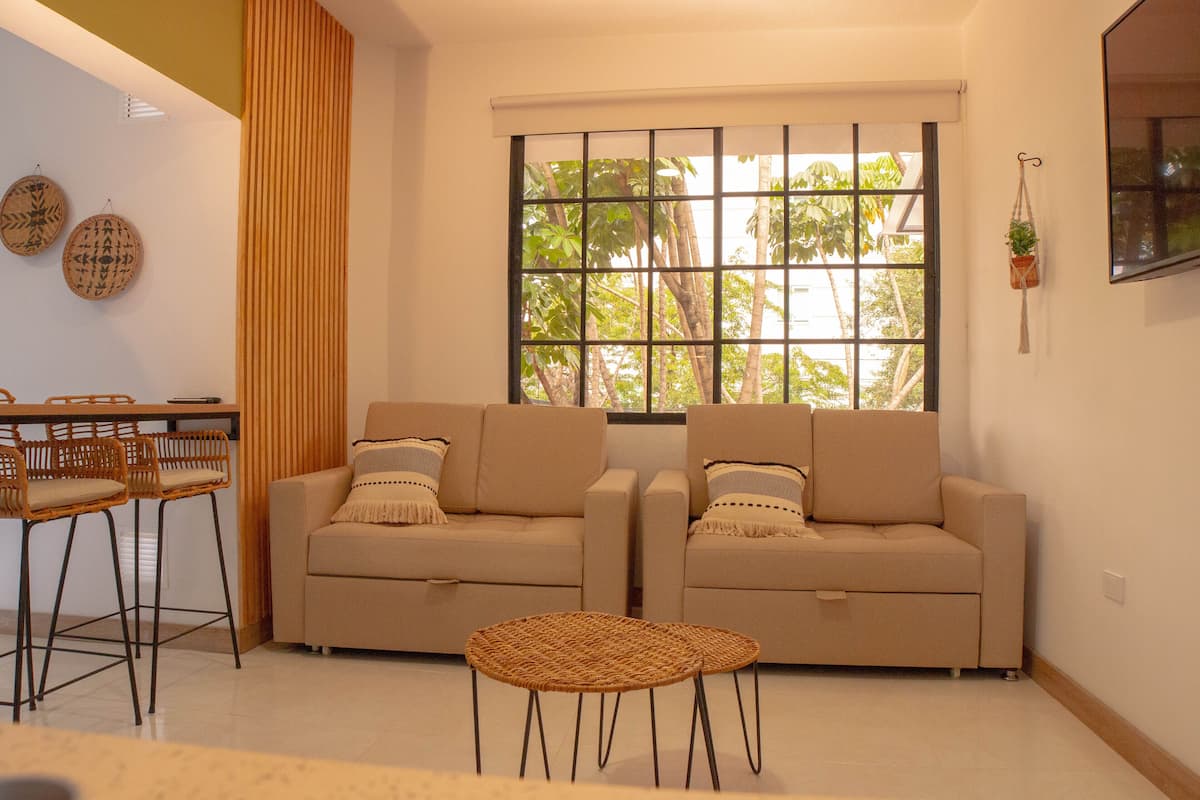Ein Wohnzimmer mit zwei Sofas, einem kleinen Tisch und einem Essbereich mit Stühlen.