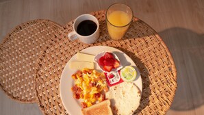 Een ontbijt bord met roerei, spek, toast, aardbeien en een glas sinaasappelsap.