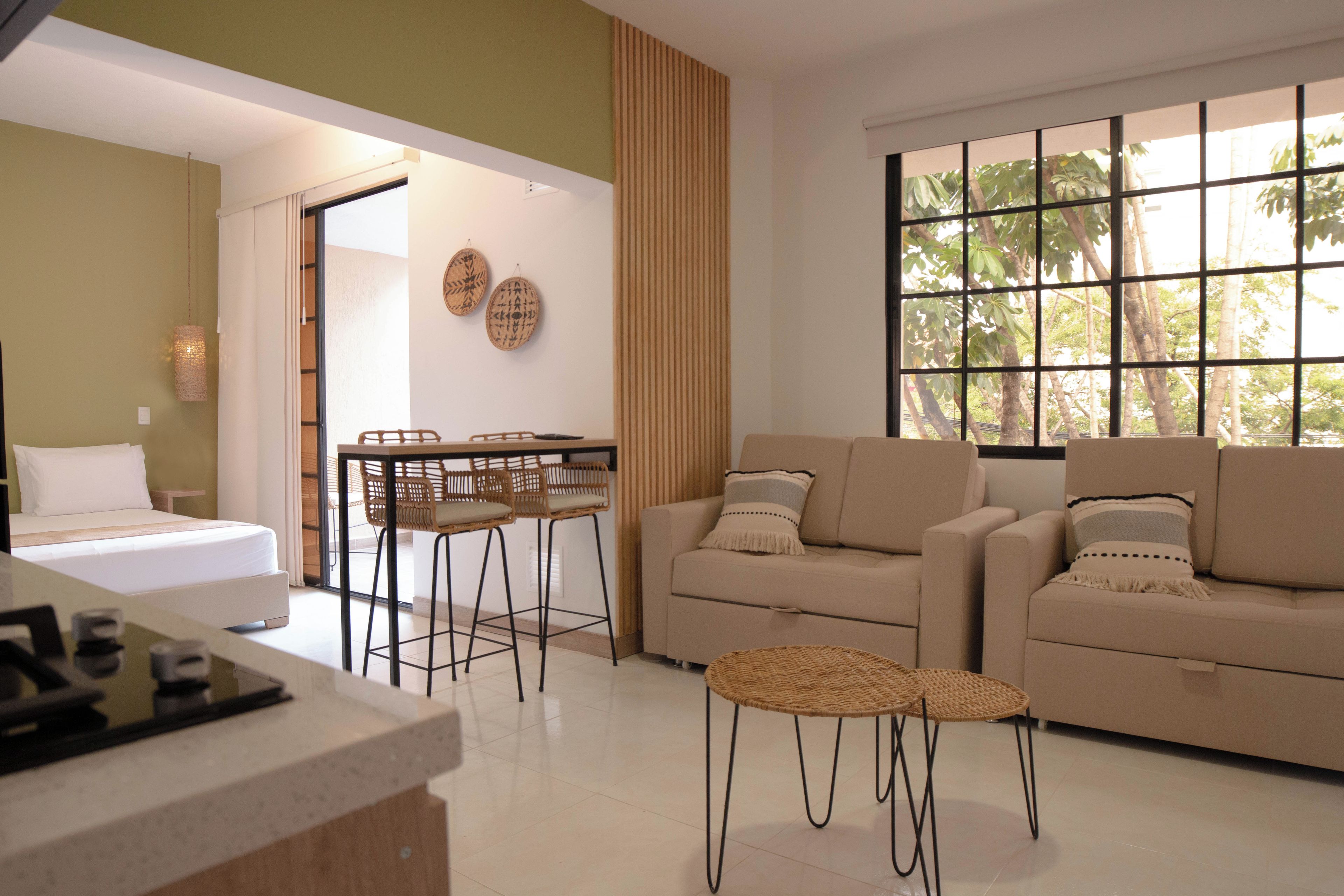A modern living room with a sofa, a dining table with chairs, and a kitchen area with a counter.