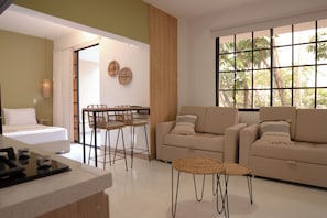 A modern living room with a sofa, a dining table with chairs, and a kitchen area with a counter. - Hotel La Casona Laureles Medellin (Medellín)