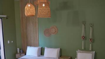 Una habitación con dos camas, una pared verde y una lámpara colgante.
