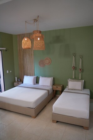 Een kamer met twee bedden, een groene wand en een hanglamp.
