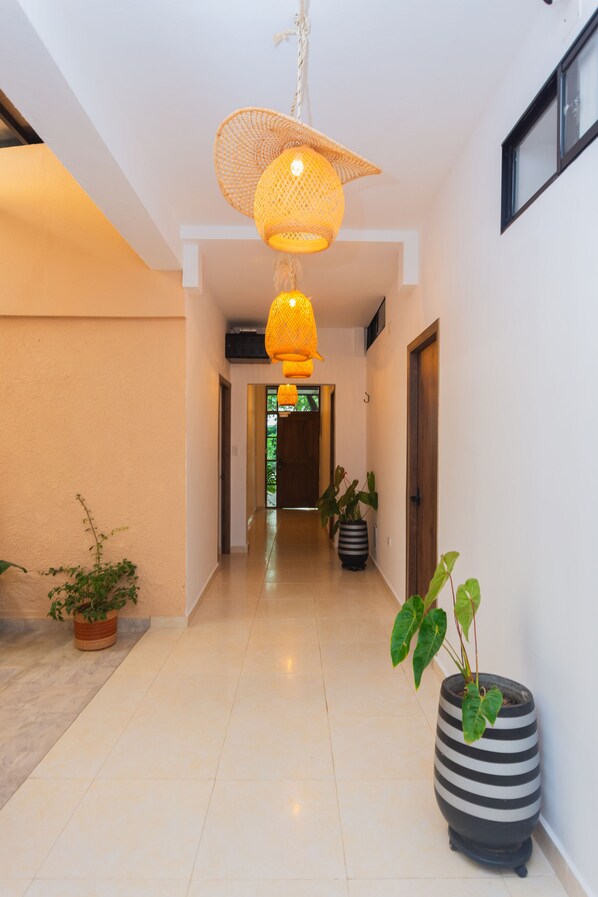 Un couloir doté d’un sol carrelé, de plantes en pot et de lampes suspendues.