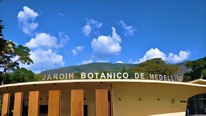 Een modern gebouw met een gebogen gevel en de tekst 'JARDIN BOTANICO DE MEDELLIN' bovenaan.