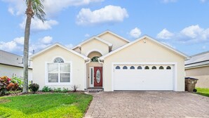 A single-story house with a red door, a garage, and a brick driveway.