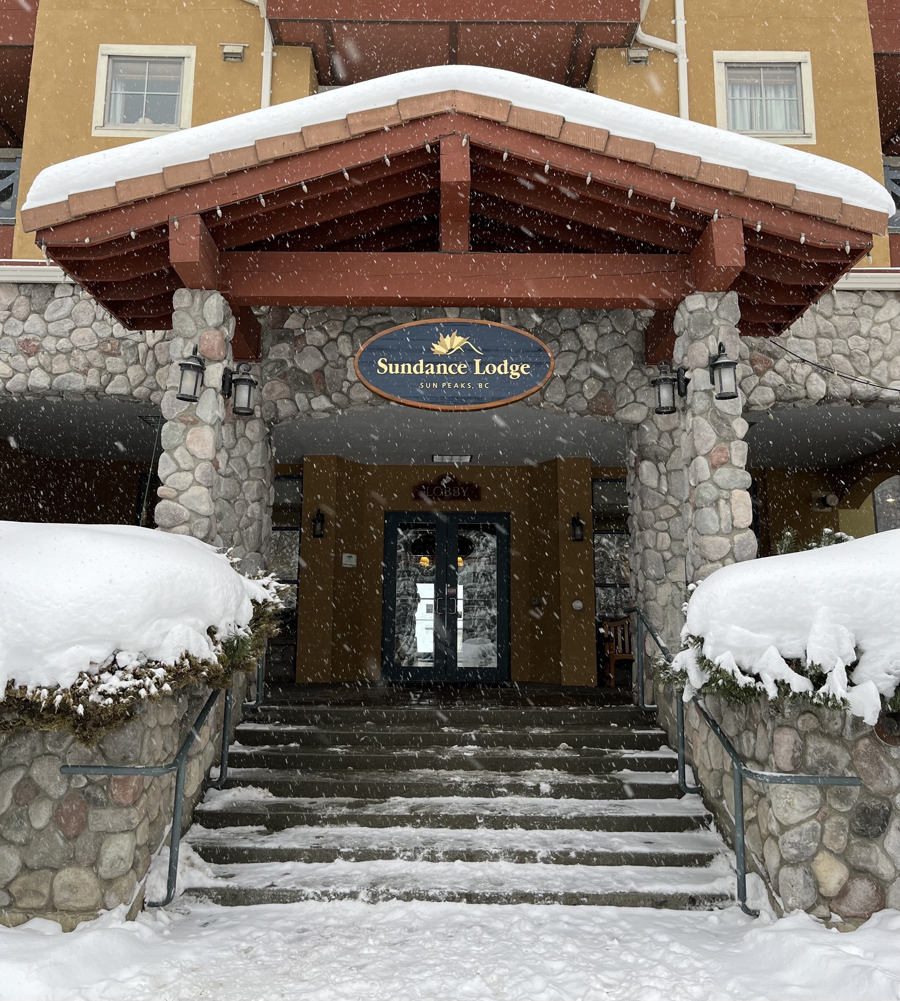La entrada de Sundance Lodge, con paredes de piedra y un alero de madera.