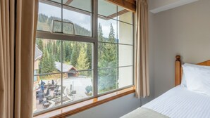 Une chambre d’hôtel avec une grande fenêtre, un lit et une vue sur un immeuble et des arbres à l’extérieur.
