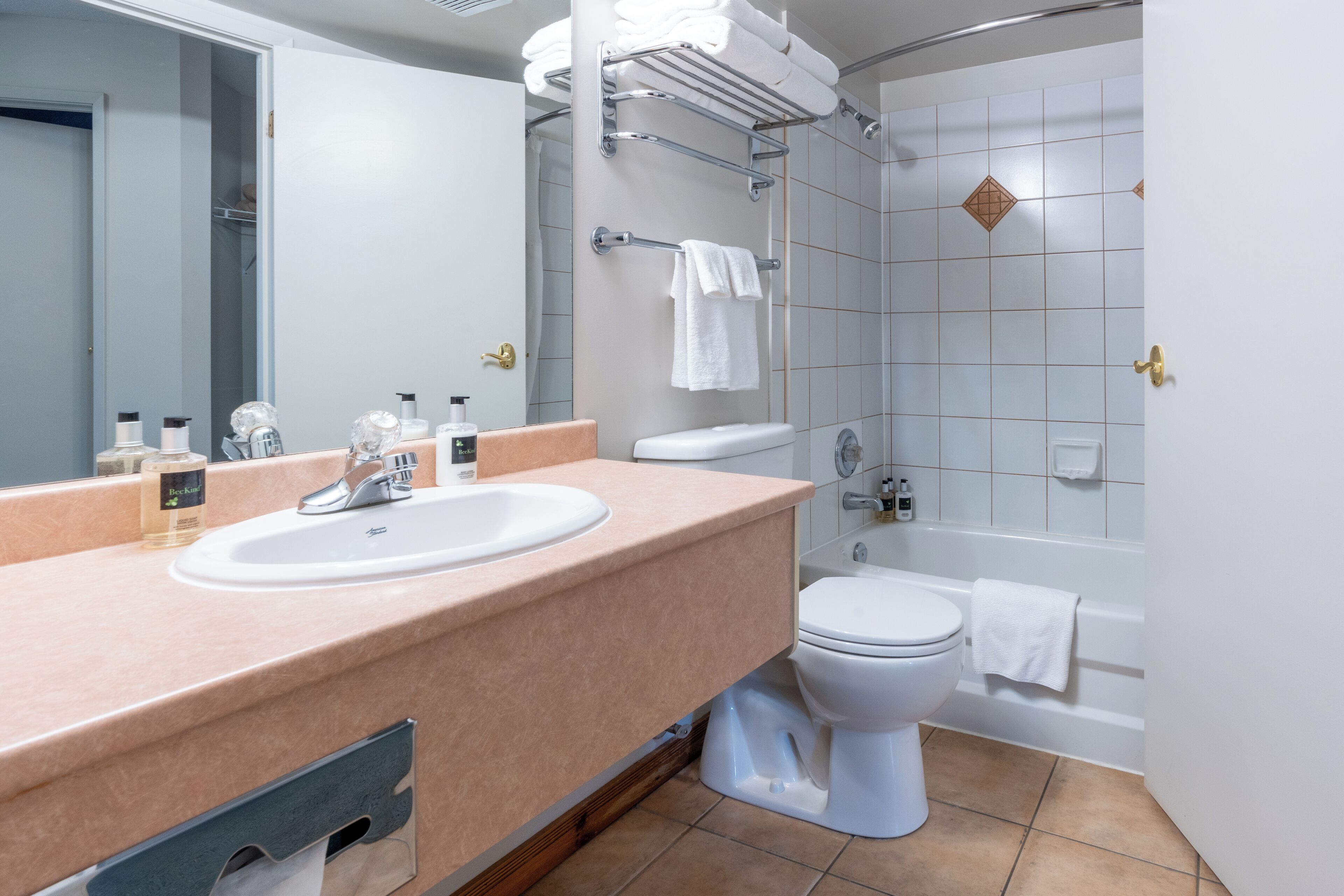 Une salle de bain moderne avec un comptoir beige, un lavabo blanc, des toilettes et une baignoire.