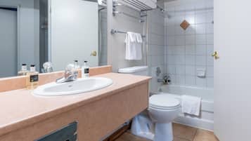 A modern bathroom with a beige countertop, a white sink, a toilet, and a bathtub.