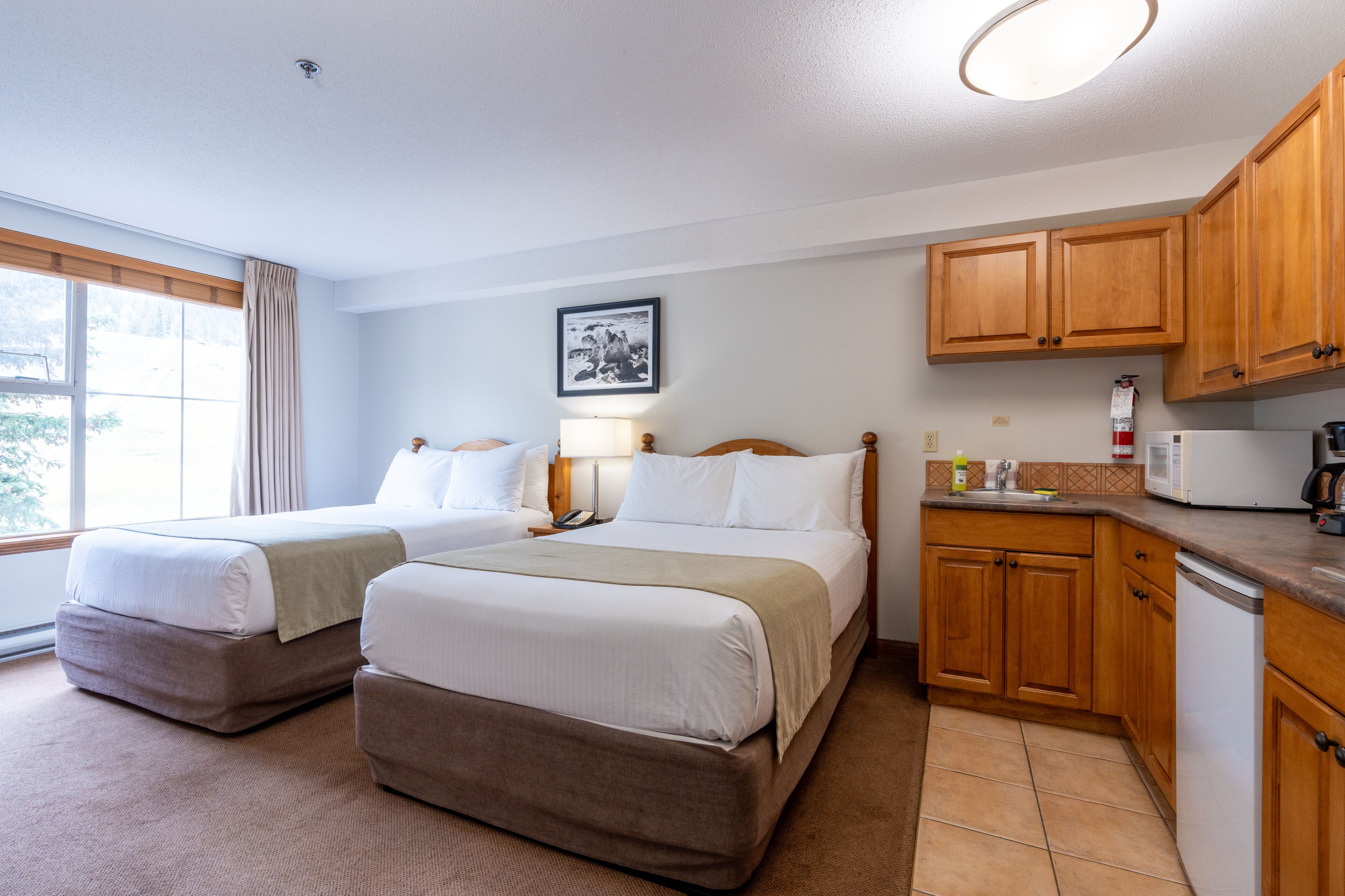 Une chambre d’hôtel avec deux lits, une kitchenette et une grande fenêtre.