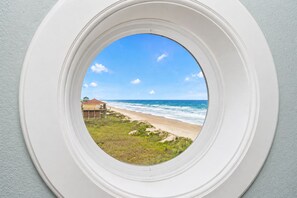 A view through a window of a beach with a house in the background. - Pet Friendly Beachfront Getaway Dream with Hot Tub & Fire Pit (Crystal Beach)
