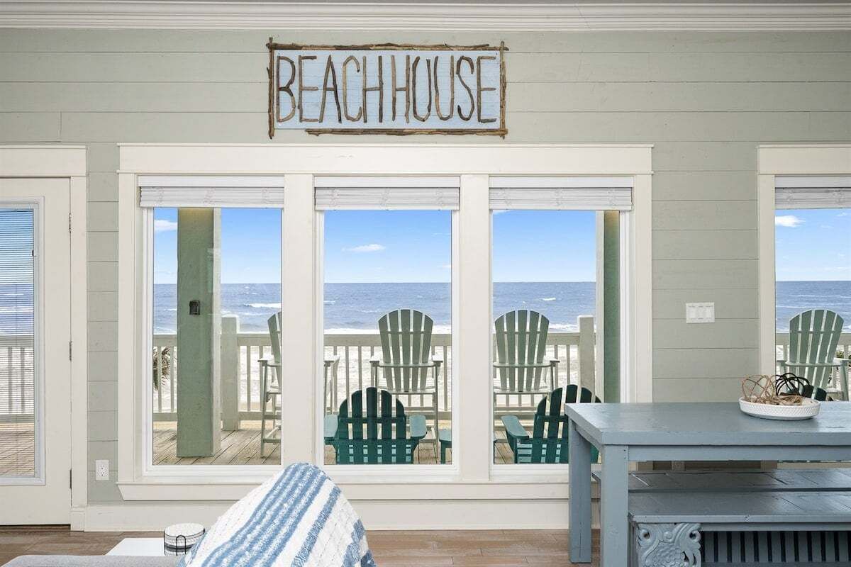A beach house with a sign reading "BEACHHOUSE" above large windows.
