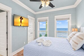 A bedroom with a bed, a television, and a view of the ocean. - Pet Friendly Beachfront Getaway Dream with Hot Tub & Fire Pit (Crystal Beach)