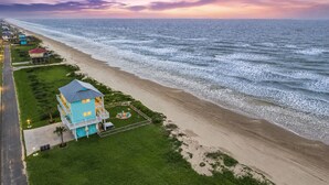 Une propriété située en bord de mer, comprenant un grand bâtiment, une pelouse bien entretenue et une vue sur l’océan.