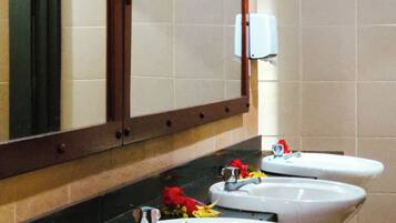 A public restroom with three sinks, a mirror, and a hand dryer.