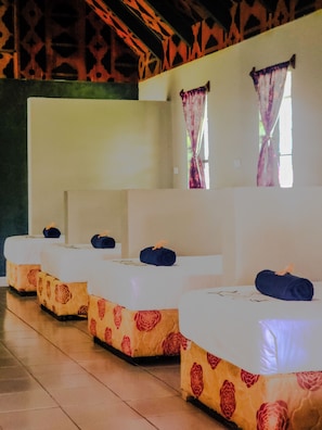 A row of beds with floral-patterned bedding, a plain wall, and a window with a curtain. - Coralview Island Resort (Tavewa Island)
