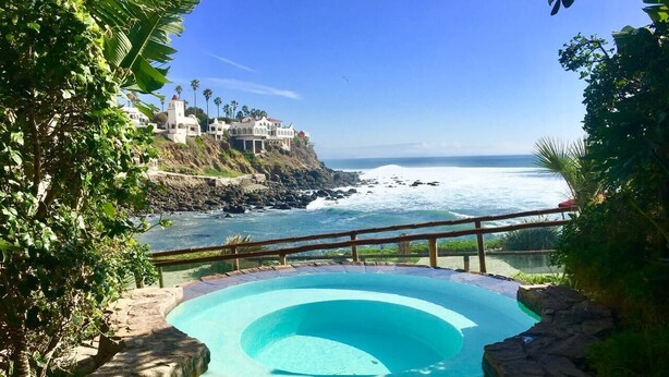 Ein Swimmingpool mit Blick auf den Ozean und ein Gebäude am Fels.