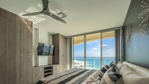 Ein Schlafzimmer mit einem großen Bett, einem Fernseher und Blick auf den Ozean.