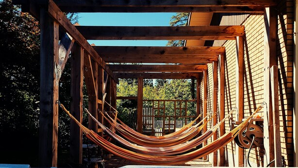 Une structure de pergola en bois, avec un hamac et un jacuzzi.