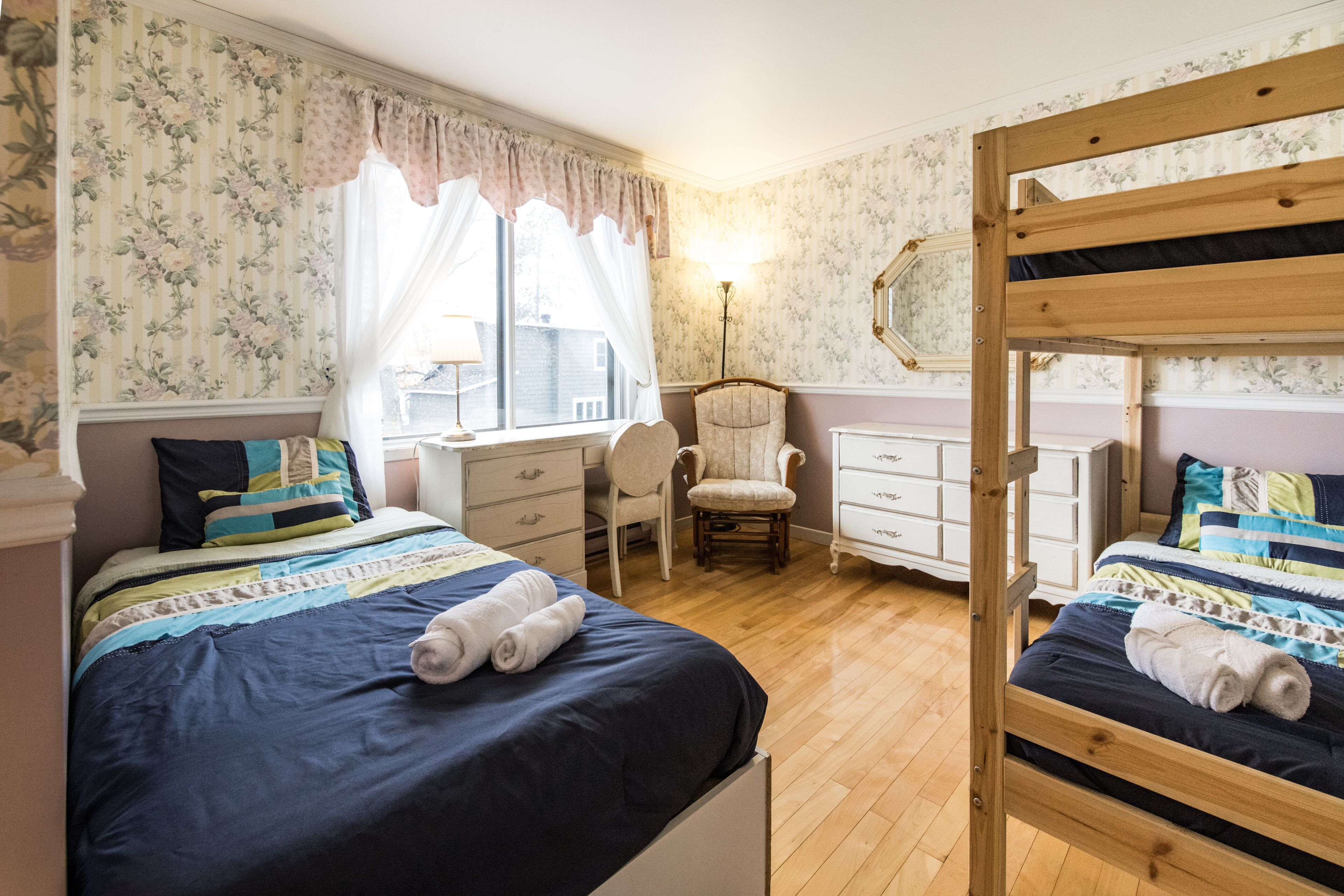 A bedroom with two beds, a chair, a dresser, and a lamp.