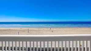 A beach view from a balcony with a railing.