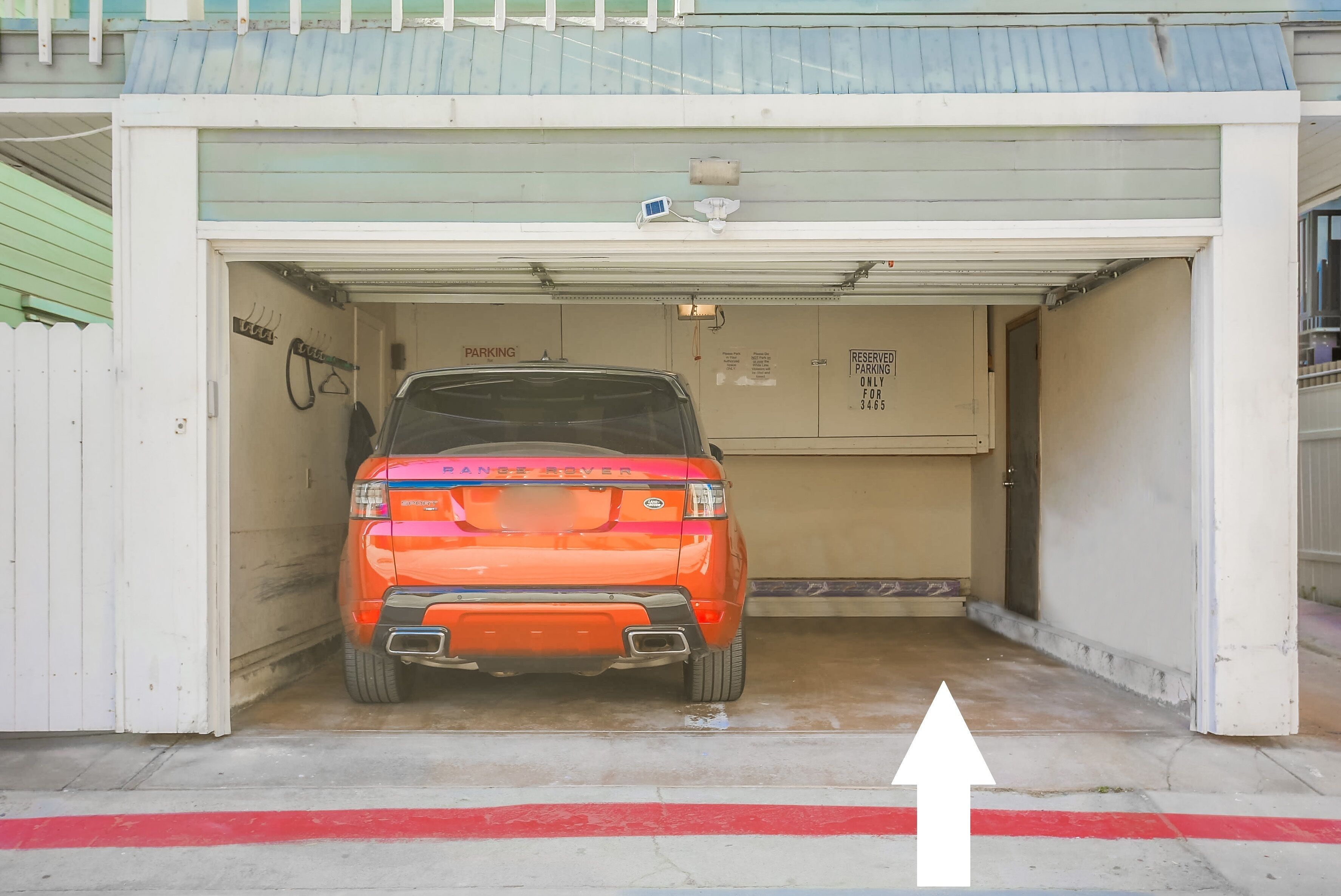 L’entrée d’un parking, avec un SUV rouge garé à l’intérieur.